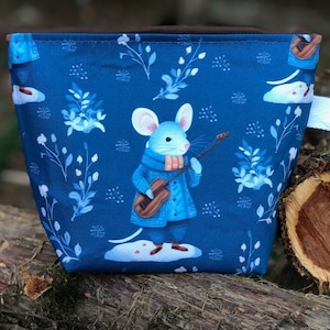 Puede incluir: Una bolsa de tela azul con una cremallera blanca y una correa blanca. La bolsa presenta un patrón repetitivo de flores blancas y un ratón tocando la guitarra sobre un fondo azul.