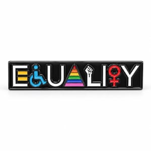 Könnte beinhalten: Eine rechteckige schwarze Emaille-Anstecknadel mit dem Wort EQUALITY in weißen Buchstaben. Das E ist ein Gleichheitszeichen, das Q ein blaues Rollstuhlsymbol, das A ein Regenbogen-Dreieck, das L eine erhobene Faust und das I ein rotes Frauensymbol.