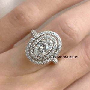 Anillo de aniversario en plata de ley con doble halo de diamantes y circonita cúbica ovalada.