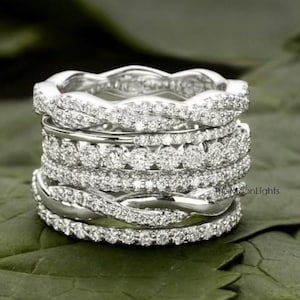 Peut inclure: Un ensemble de six bagues en argent avec un design délicat et scintillant de diamants. Les bagues sont empilées les unes sur les autres, créant un look superposé.