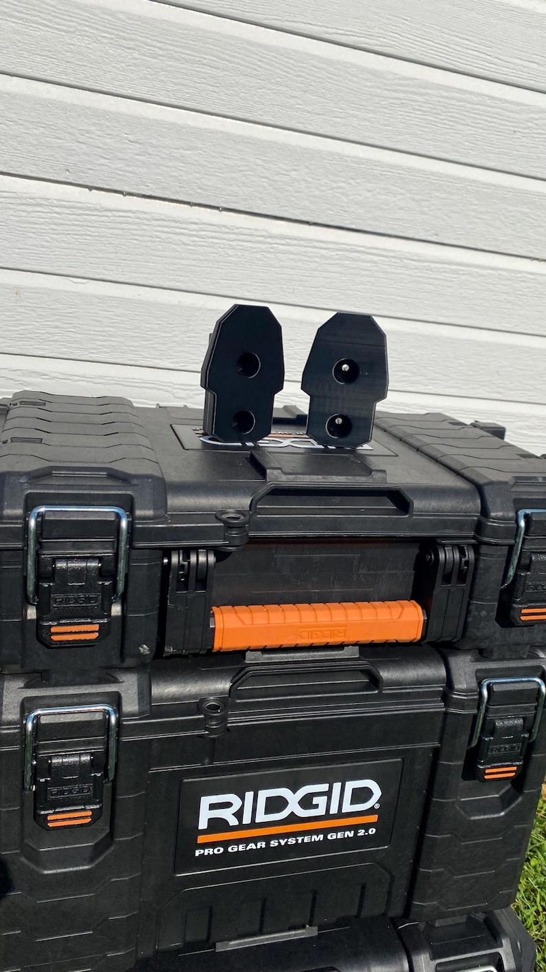 May include: Black toolboxes with orange accents and the "RIDGID PRO GEAR SYSTEM GEN 2.0" logo. Two black attachments are on top of the toolbox. The toolboxes are stacked on top of each other.