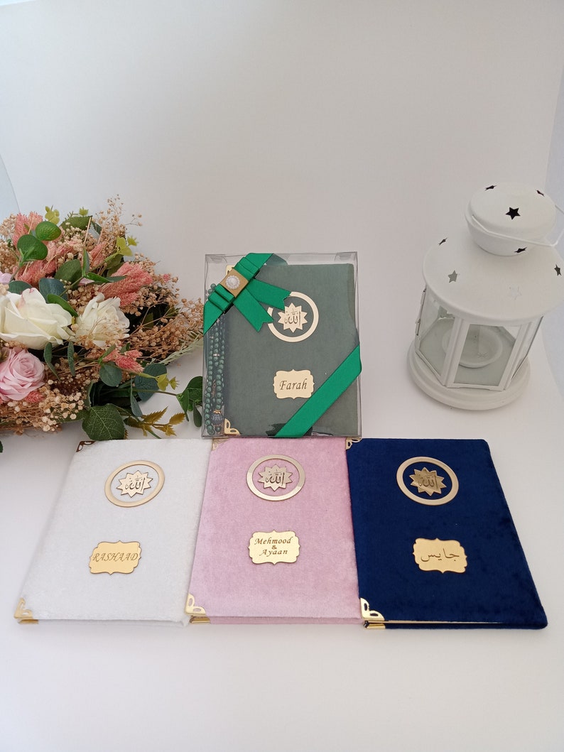 May include: Four rectangular books with velvet covers in white, pink, dark blue, and sage green. Each book features gold-toned metal corner protectors, a circular emblem with Arabic calligraphy, and a rectangular nameplate with custom text.