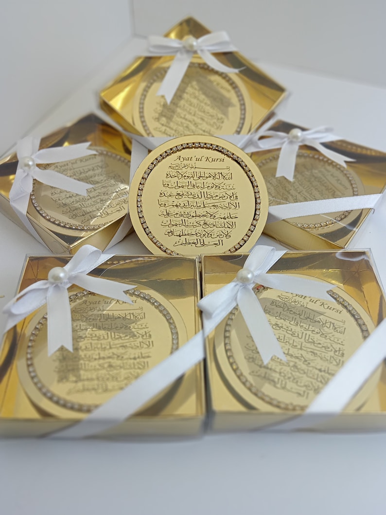 May include: Gold-colored decorative round boxes with white ribbon and pearl accents. Each box contains a gold-colored round plaque with Arabic calligraphy and the text "Ayatul Kursi".