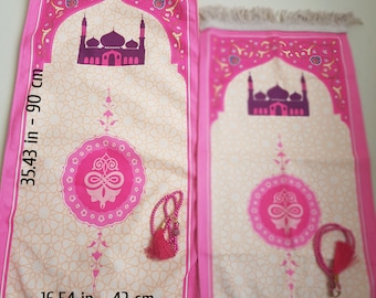 Peut inclure: Deux tapis de prière rose et crème avec une silhouette de mosquée et des motifs géométriques, accompagnés de deux chapelets roses. Le plus grand tapis mesure 90 cm sur 42 cm, tandis que le plus petit présente un motif identique.