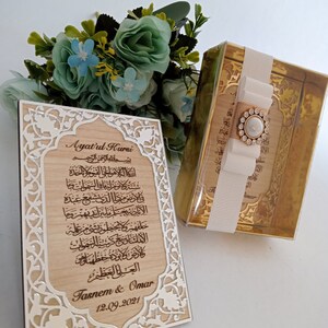 May include: A wooden plaque with an intricate silver design and a carved inscription of the Ayatul Kursi, a verse from the Quran. The plaque also includes the names "Tasnem & Omar" and the date "12.09.2021".