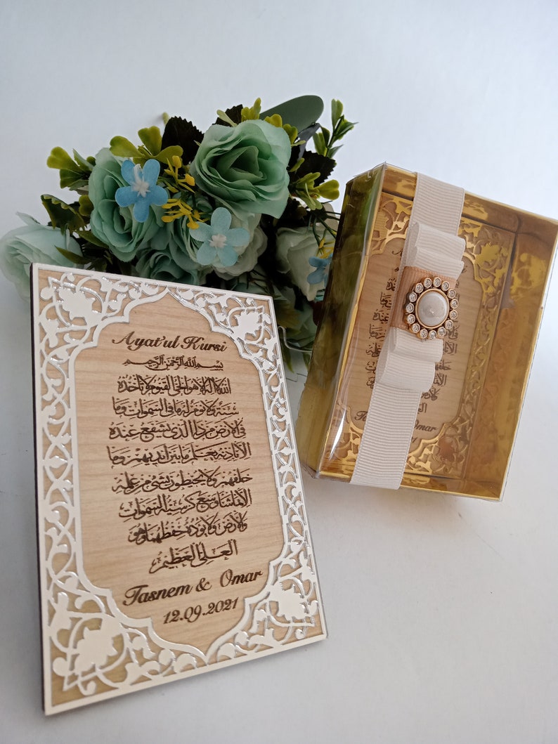 May include: A wooden plaque with an intricate silver design and a carved inscription of the Ayatul Kursi, a verse from the Quran. The plaque also includes the names "Tasnem & Omar" and the date "12.09.2021".