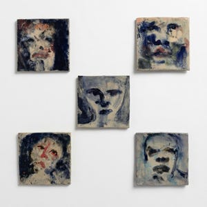 May include: Five square ceramic tiles arranged in a cluster, each featuring a hand-painted portrait in shades of deep blue, black, and muted red. The brushwork is expressive and loose, depicting abstract human faces on a light, off-white background.