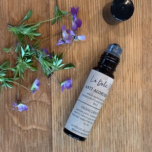 Puede incluir: Un frasco de vidrio marr&oacute;n con una tapa negra y una etiqueta blanca que dice "La Dolce Villa Anti-Aging Serum Made with Natural Ingredients and Essential Oils Ingredients: Yarrow Pom, Frankincense, Myrrh, Helichrysum, Lavender Essential Oils 10 ml @ladolcevilla"