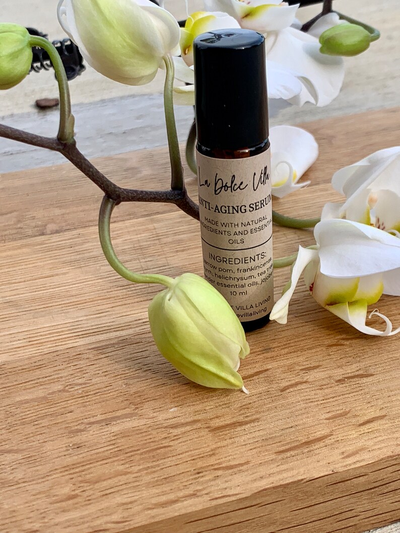 Puede incluir: Un frasco de vidrio marr&oacute;n con un tap&oacute;n negro y una etiqueta blanca que dice "La Dolce Vita Anti-Aging Serum Made with Natural Ingredients and Essential Oils Ingredients: Myrrh, Frankincense, Helichrysum, Tea Tree, Jojoba Essential Oils, 10 ml Villa Living villaliving"