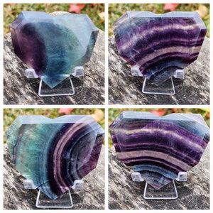 May include: Four heart-shaped fluorite crystals with different banding patterns. The crystals are a mix of green, purple, and white. They are displayed on clear stands.