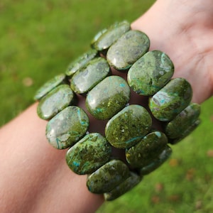May include: A green and blue gemstone bracelet with oval-shaped beads. The bracelet is made of natural stones and has a unique, earthy look.