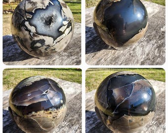May include: Four polished agate spheres with different patterns and colors. The spheres are all about 3 inches in diameter and have a smooth, shiny surface. The colors range from black to white with shades of brown and gray.