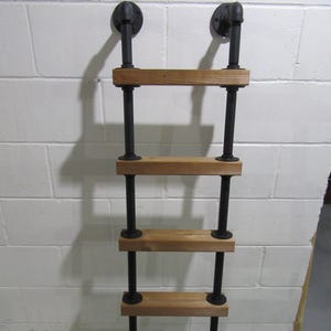 May include: A rustic, industrial-style ladder shelf. The shelf features four wooden shelves supported by black metal pipes and fittings. The ladder is designed to be mounted on a wall, with two black metal brackets at the top.