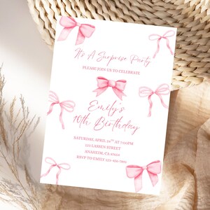Könnte beinhalten: Eine weiße Einladungskarte mit rosa Aquarellschleifen. Der Text lautet "It's A Surprise Party" und "Emily's 10th Birthday". Die Karte enthält Datum, Uhrzeit, Adresse und RSVP-Informationen. Das Design wird durch rosa Schleifen ergänzt.