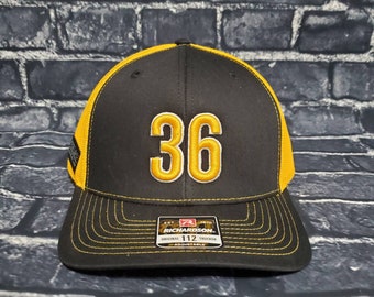 May include: Black and yellow trucker hat with the number 36 embroidered on the front. The hat is adjustable and has a Richardson 112 label.