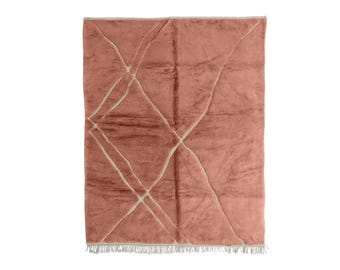Puede incluir: Una alfombra rectangular de color terracota con un diseño geométrico de líneas entrecruzadas en blanco roto. La alfombra tiene un borde con flecos. Dimensiones no visibles.