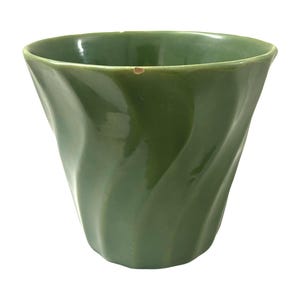 May include: A green ceramic planter with a wavy design. The planter is glazed and has a smooth finish.