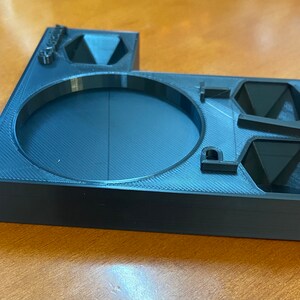 May include: A black 3D printed dice tray with compartments for different dice shapes. The tray has a circular indentation in the center and the word "Dice" is printed on the side.