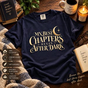 May include: A navy blue short-sleeve t-shirt featuring gold text that reads My Best Chapters Begin After Dark, accompanied by a crescent moon and star graphic. The shirt has a crew neckline and a Comfort Colors brand label at the inner collar.