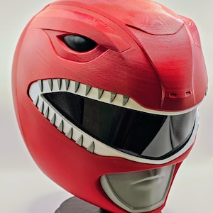 May include: A red plastic helmet with a white visor and a white, toothy mouth. The helmet has a black eye opening on each side.