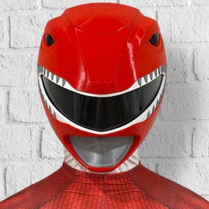 May include: Red plastic Power Ranger helmet with a white visor and a white and gray mouth guard. The helmet has a dinosaur-like design with white teeth.