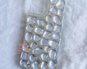 May include: A clear phone case with a iridescent, textured design that resembles a mosaic of small, rounded stones.