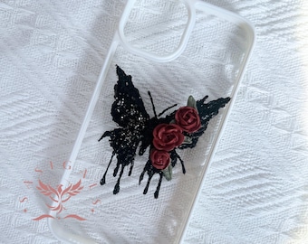 May include: A clear phone case with a black butterfly design and red roses. The butterfly has glitter accents and the roses are 3D.