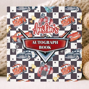 May include: An autograph book with a checkered pattern and cartoon car illustrations. The book has the text "Austin's AUTOGRAPH BOOK" and a red and silver emblem. A teddy bear with a bow tie is next to the book.