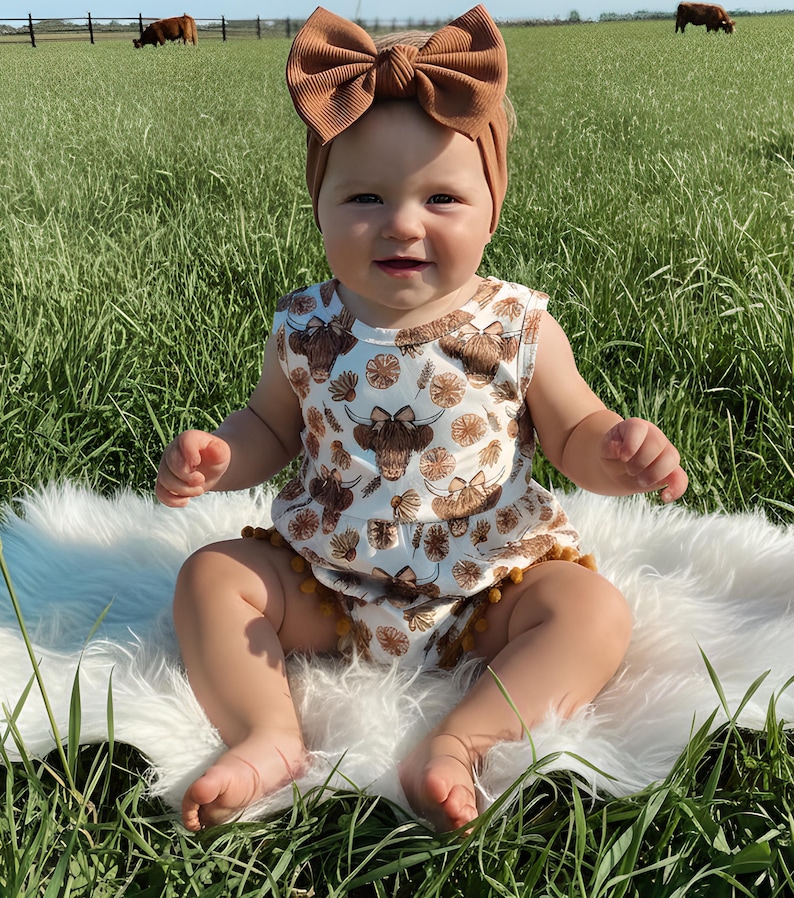 Adorable western themed baby girl outfit featuring a floral highland cow design and pom trim, perfect for summer adventures, family photos, and everyday wear. A charming baby clothing choice and memorable baby shower gift idea.