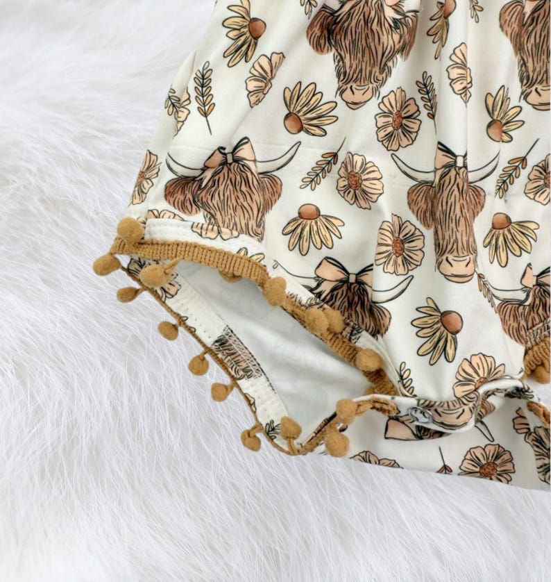 Western summer baby girl outfit featuring a floral highland cow romper, breathable fabric, and playful pom trim. A beautiful baby clothing piece that works as a baby gift for girls, newborn present, or baby shower gift.