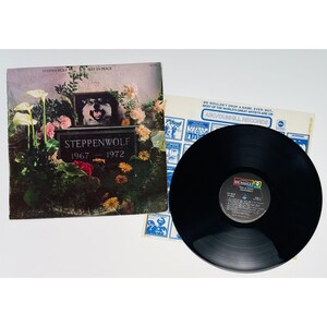 May include: A Steppenwolf Rest in Peace 1967-1972 vinyl record album cover featuring a tombstone with a wolf portrait surrounded by flowers, alongside a black vinyl record and a white inner sleeve with blue text and ABC/Dunhill Records branding.