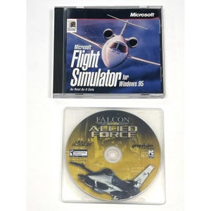 May include: A Microsoft Flight Simulator for Windows 95 CD-ROM in a clear plastic jewel case, featuring a white airplane on the cover. Below it is a Falcon 4.0 Allied Force PC game disc in a clear plastic case, displaying a fighter jet graphic.