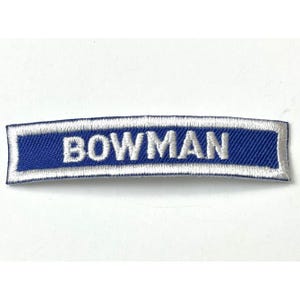 May include: A blue and white embroidered patch with the word "BOWMAN" in white lettering.
