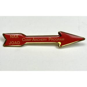 May include: A red and gold arrow-shaped pin with the text "NAA JOAD CAMP ARCHERY PROGRAM" on it.