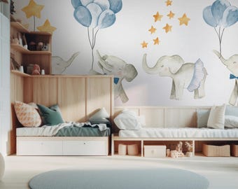 Puede incluir: Un mural de pared con ilustraciones en acuarela de elefantes de color gris claro, algunos con pajaritas o faldas azules, que sostienen racimos de globos azules y están rodeados de estrellas amarillas sobre un fondo blanco.