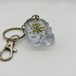 Handmade white starburst pressed flower resin skull keychain