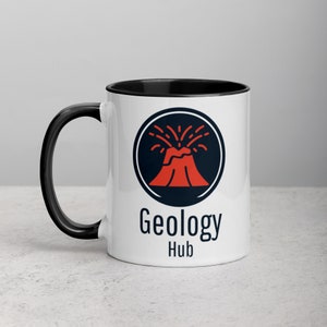 Puede incluir: Taza de cerámica blanca con borde y asa negros. La taza presenta un gráfico de volcán negro y rojo con el texto "Geology Hub".