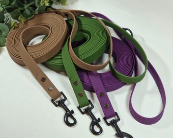 May include: A collection of dog leashes in various colors, including brown, green, and purple. Each leash is rolled up and features a matching handle with metal hardware. The leashes are made of a durable material and are designed for pet owners.
