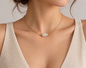 May include: A gold chain necklace featuring a single, smooth, cylindrical white stone bead at the center. The bead is capped on both ends with small, polished gold-toned metal accents that connect directly to the delicate gold link chain.