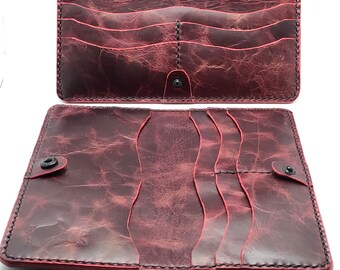 May include: A burgundy leather wallet with multiple card slots and a snap closure. The wallet is distressed and has a vintage look.