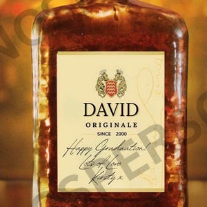 May include: A rectangular bottle of Disaronno liqueur with a dark brown liquid. The label reads "DAVID ORIGINALE SINCE 2000" with a crest. Handwritten text says "Happy Graduation! Lots of Love Kirsty x."