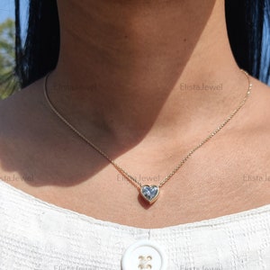 May include: A gold chain necklace with a heart-shaped pendant featuring a clear, faceted gemstone.