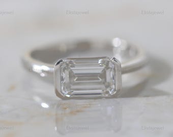 May include: A silver ring with a clear emerald-cut gemstone.