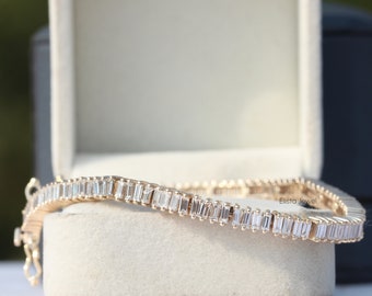 May include: A gold bracelet with a row of baguette-shaped diamonds. The bracelet is in a white box with the text "Elista Jewel" on the side.