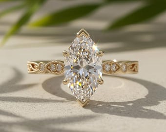 Op de afbeelding: Een gouden ring met een grote marquise-geslepen middensteen die door zes klauwen wordt vastgehouden. De band is versierd met gedetailleerd filigraan metaalwerk en kleine ronde accentstenen die langs de zijkanten zijn ingelegd.