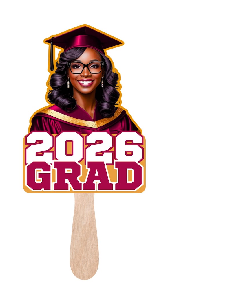 May include: A graduation fan featuring a smiling graduate in a maroon cap and gown. The fan displays the text "2026 GRAD" in maroon and white, with a gold border, and a wooden handle.