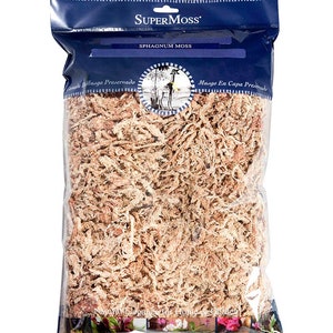 May include: A clear plastic bag filled with dried, light brown sphagnum moss. The bag has a blue label with the text "SUPERMOSS" and "SPHAGNUM MOSS".