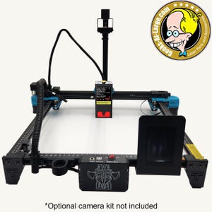 以下が含まれることがあります： 黒とティール色のレーザー彫刻機。黒いコントロールパネルとスクリーンを備えています。マシンは、測定マークと赤いレーザーモジュールを備えた黒いフレームです。「Geeks-At-Large.com」の文字が右上隅にあります。「*Optional camera kit not included」の文字が下にあります。