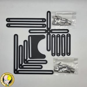 May include: A set of black metal slotted brackets and plates for laser engraving machines, including two small plastic bags containing silver-colored metal thumb screws and nuts. The components feature various lengths and shapes with pre-cut slots.