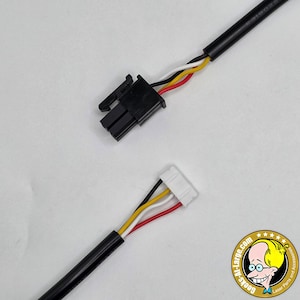May include: Two black electrical cables with connectors. One connector is black, and the other is white. Each cable has four wires: black, white, yellow, and red. The cables are on a white background. A logo is in the bottom right corner.